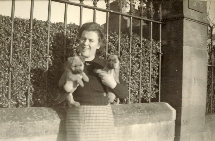Lady holding two puppies, outside (probably)